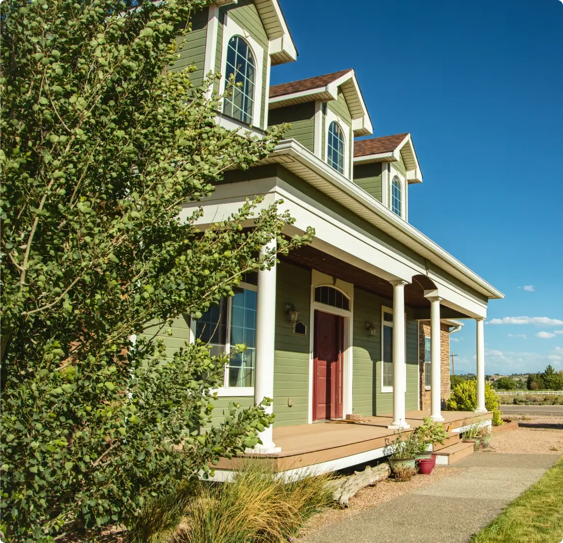 Green house with porch and blue sky